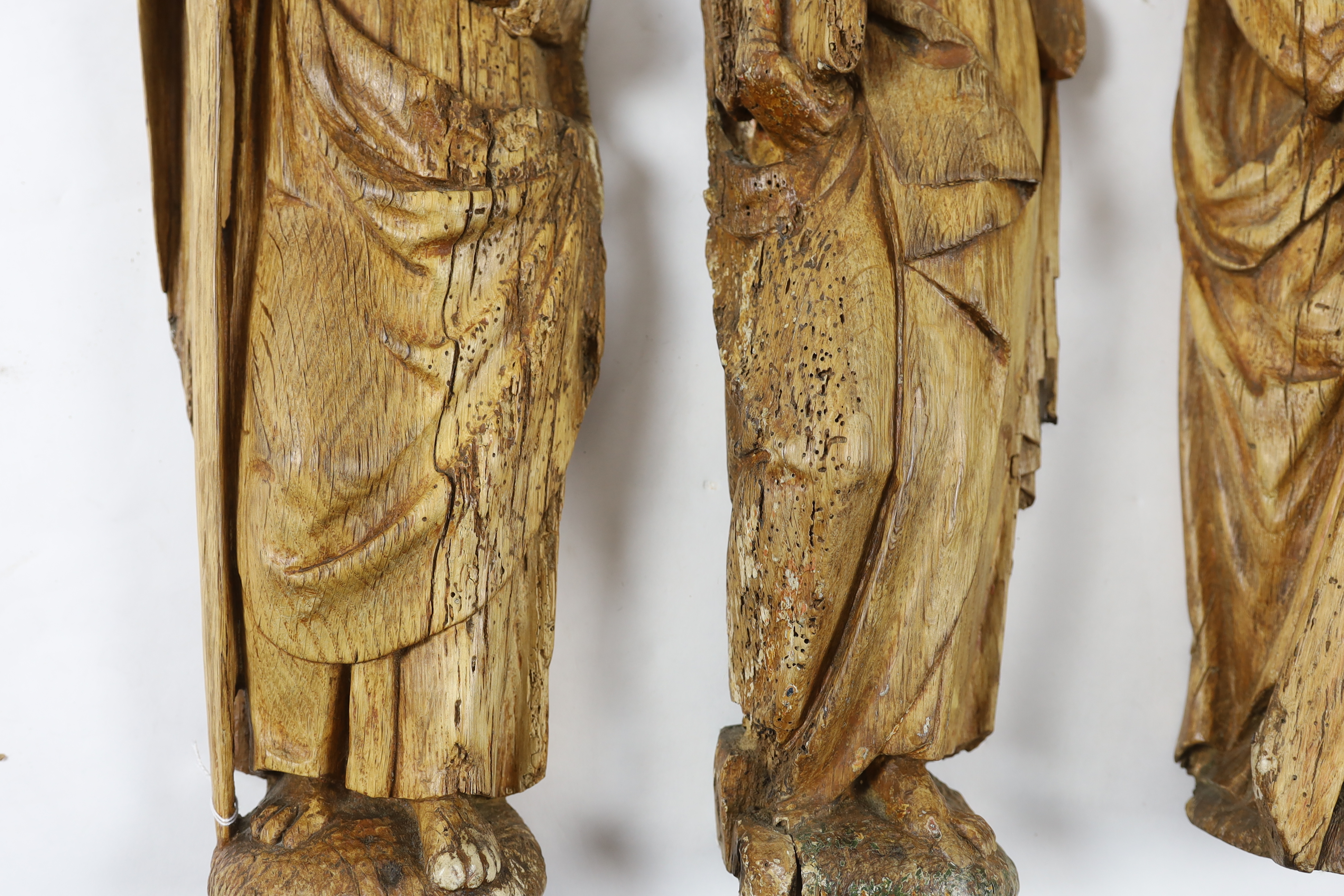 A set of three 18th century Continental carved wood figures of Saints, largest 17cm wide, 58cm high